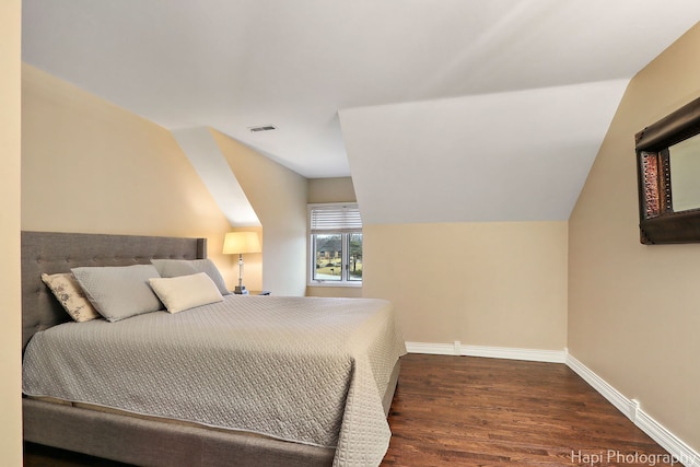 bedroom featuring visible vents, baseboards, lofted ceiling, and wood finished floors