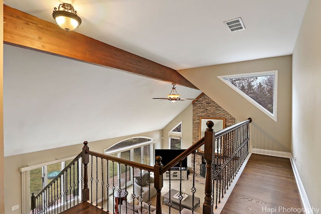 hallway with a wealth of natural light, visible vents, baseboards, and wood finished floors