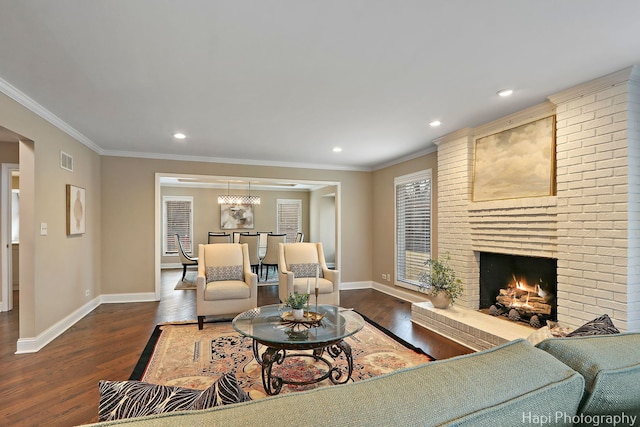 living area with ornamental molding, a brick fireplace, baseboards, and wood finished floors