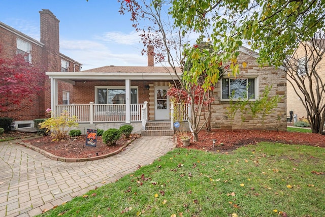 ranch-style house featuring covered porch, stone siding, brick siding, and a front yard