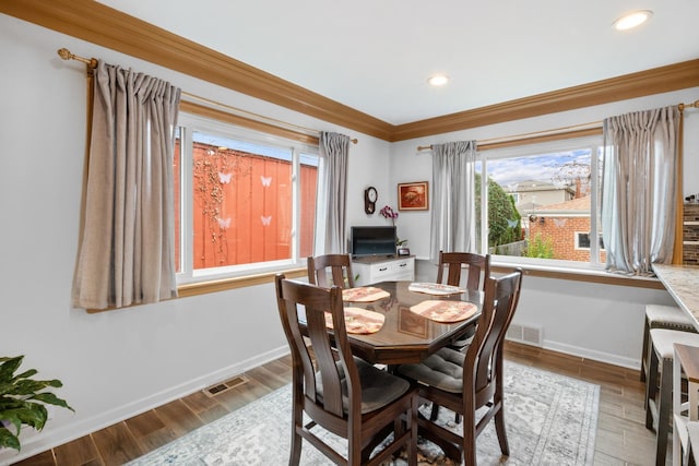 dining room featuring ornamental molding, wood finished floors, visible vents, and baseboards