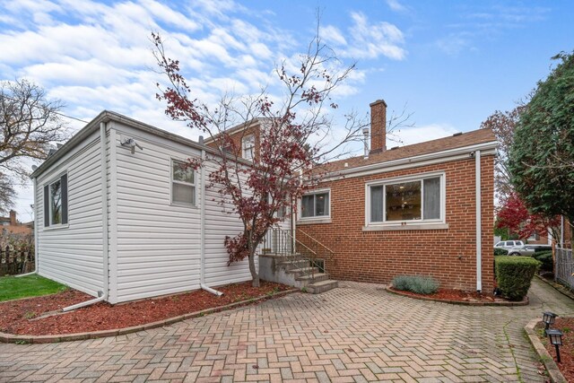 back of property featuring brick siding, a patio, and a chimney