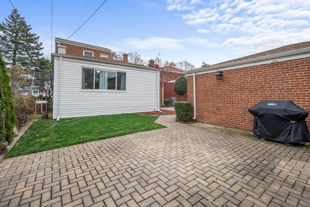 rear view of house with brick siding, fence, and a patio