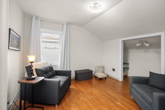 living room with vaulted ceiling, baseboards, and wood finished floors