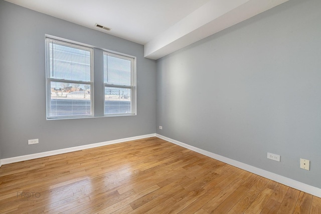 spare room with light wood-type flooring, baseboards, and visible vents