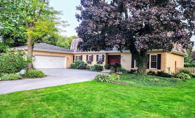 view of front of house featuring a garage, brick siding, aphalt driveway, fence, and a front yard