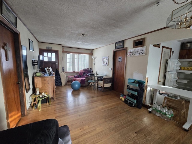 living area with ornamental molding, a textured ceiling, and wood finished floors