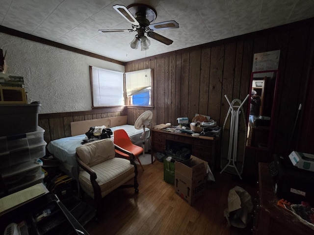 interior space featuring a textured wall, wood walls, wood finished floors, and a ceiling fan