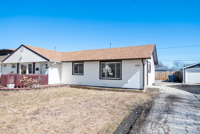 single story home featuring a shingled roof, fence, and an outbuilding