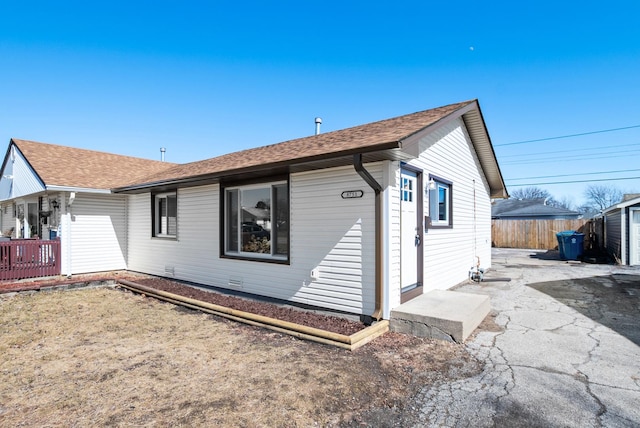 back of property with fence, a patio, and roof with shingles