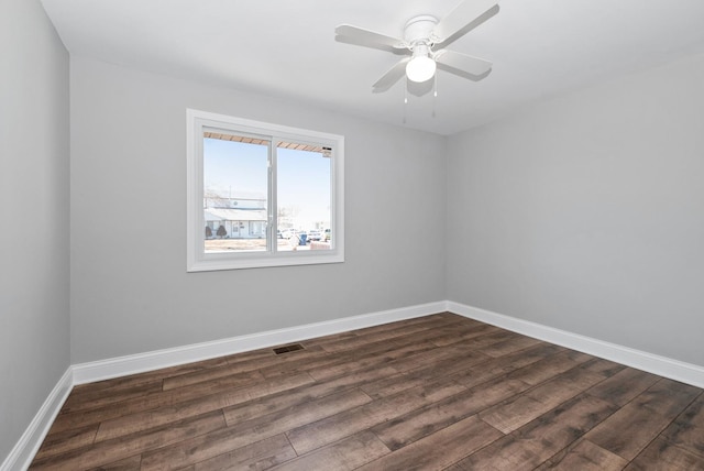 spare room featuring baseboards, dark wood finished floors, and a ceiling fan