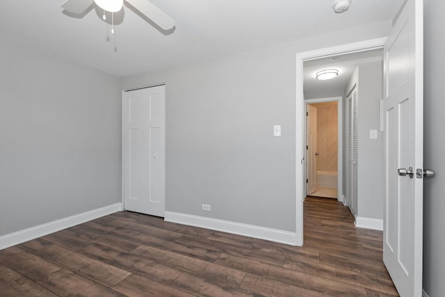 unfurnished bedroom featuring ceiling fan, a closet, dark wood finished floors, and baseboards