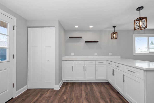 kitchen with a peninsula, white cabinets, light countertops, dark wood-style floors, and open shelves