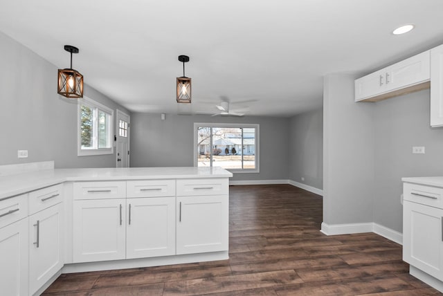 kitchen featuring dark wood-style floors, light countertops, white cabinets, a peninsula, and baseboards