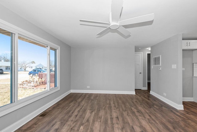 spare room featuring dark wood-style floors, visible vents, and baseboards