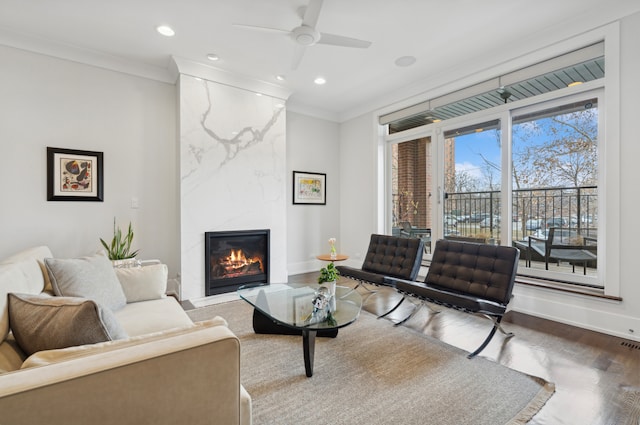 living room with ornamental molding, wood finished floors, recessed lighting, a premium fireplace, and baseboards