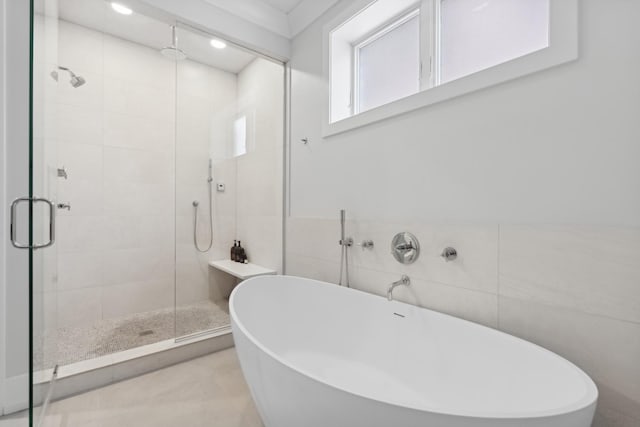 full bathroom with tile walls, a freestanding tub, and a stall shower