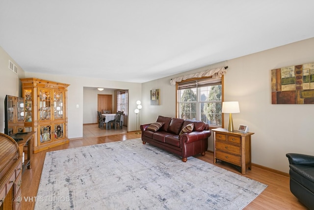 living room featuring light wood-type flooring, visible vents, and baseboards