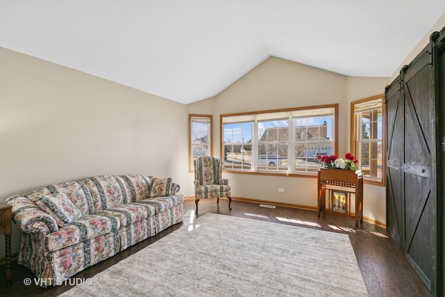 living room featuring a barn door, visible vents, baseboards, dark wood finished floors, and vaulted ceiling