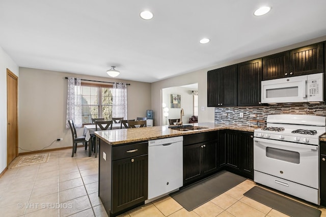 kitchen with light tile patterned floors, decorative backsplash, a sink, white appliances, and a peninsula