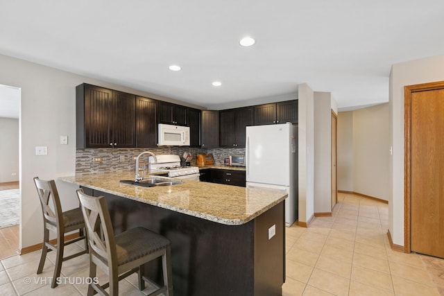 kitchen with light stone counters, a peninsula, white appliances, a sink, and tasteful backsplash