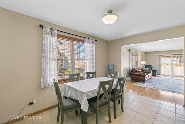 dining area with light tile patterned floors, plenty of natural light, and baseboards