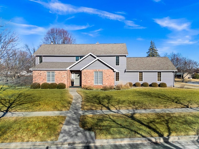 traditional home with a front lawn, brick siding, and roof with shingles