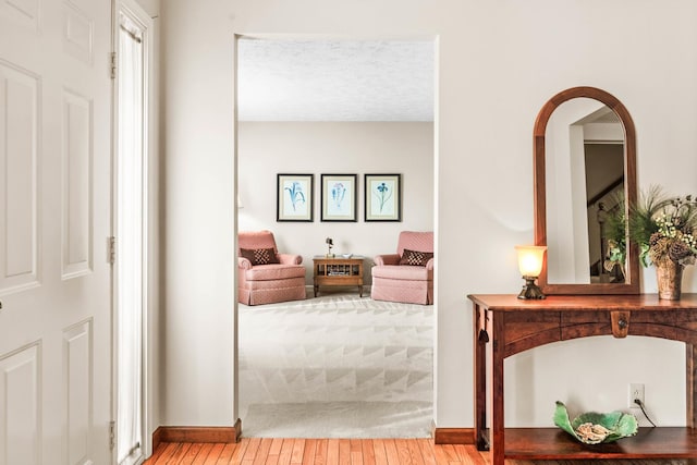 interior space with a textured ceiling, baseboards, and hardwood / wood-style flooring