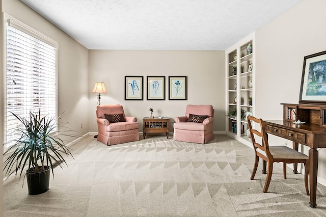 living area featuring baseboards, light colored carpet, and a textured ceiling