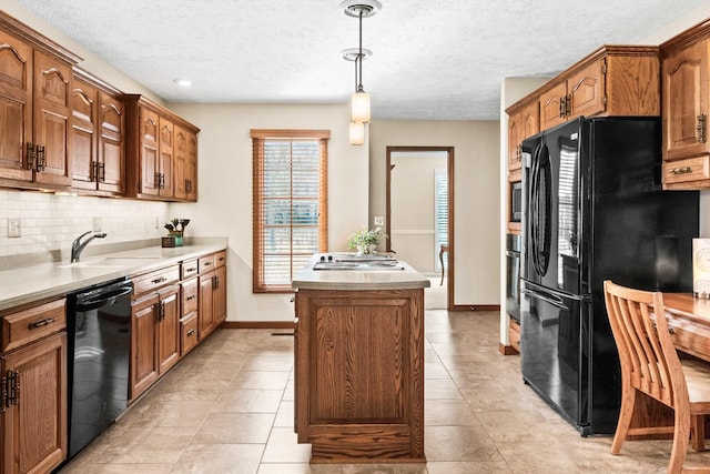 kitchen with a kitchen island, black appliances, light countertops, decorative light fixtures, and backsplash