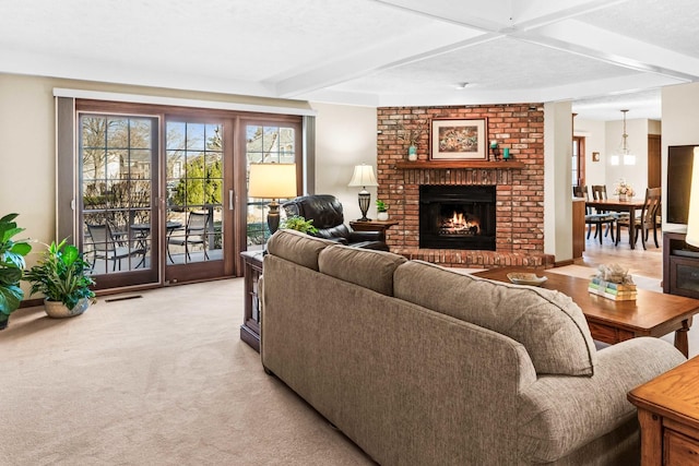 living area featuring beam ceiling, a brick fireplace, light colored carpet, and visible vents