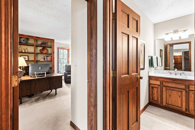 bathroom with vanity, baseboards, and a textured ceiling