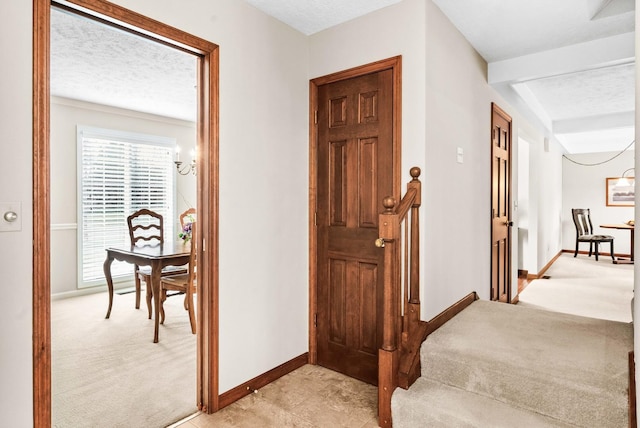 hall featuring baseboards, light carpet, and a textured ceiling