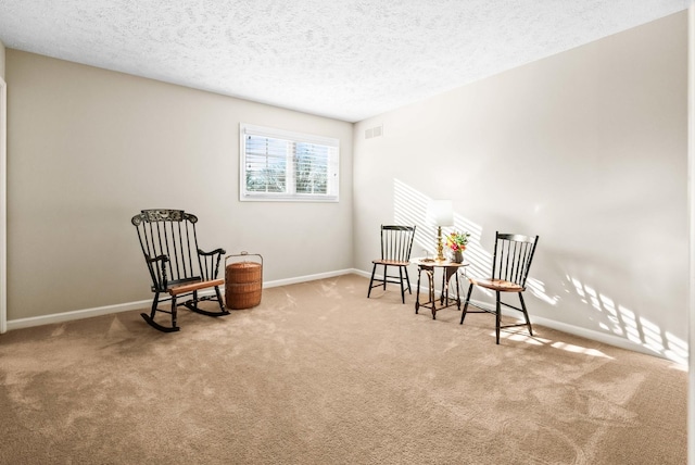 living area featuring carpet flooring, baseboards, visible vents, and a textured ceiling