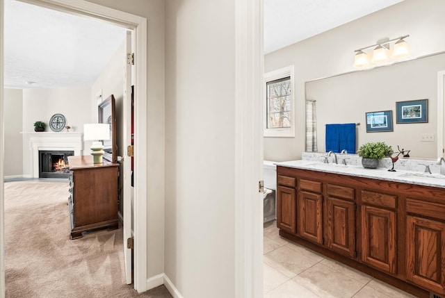 bathroom with a sink, a fireplace with flush hearth, double vanity, and tile patterned flooring