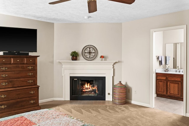 carpeted living room with a glass covered fireplace, a textured ceiling, a ceiling fan, and a sink