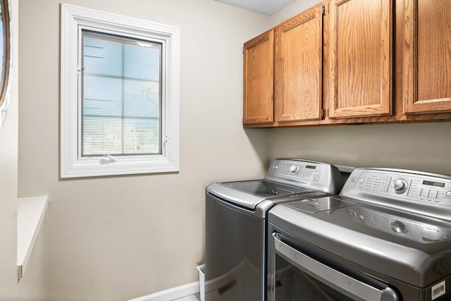 laundry room with cabinet space, washer and dryer, and baseboards