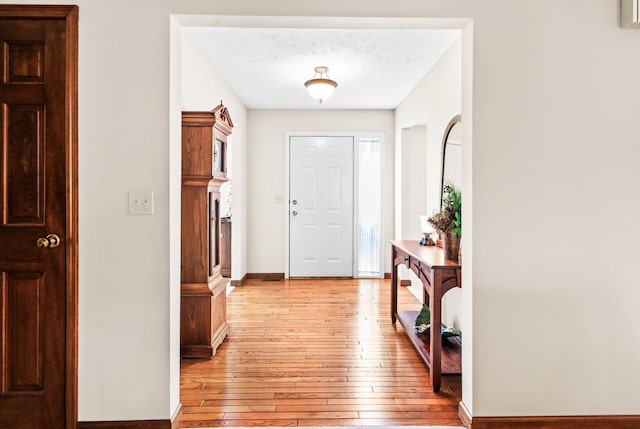 entrance foyer featuring baseboards, light wood-type flooring, and a textured ceiling