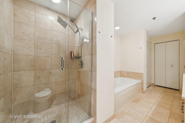 bathroom with a shower stall, a bath, and tile patterned floors