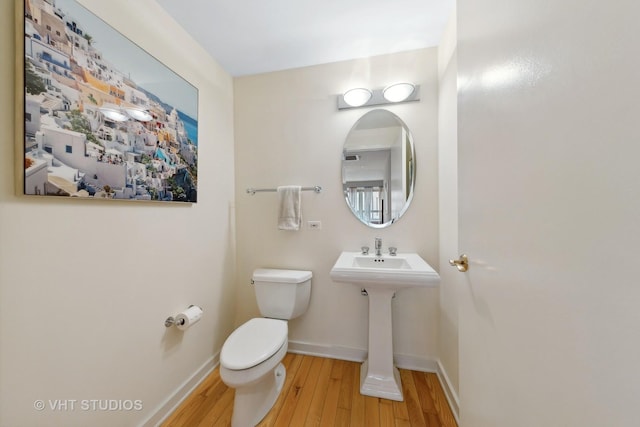 bathroom with toilet, baseboards, and hardwood / wood-style floors