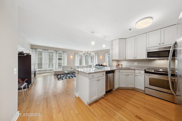 kitchen with a peninsula, white cabinetry, appliances with stainless steel finishes, and open floor plan