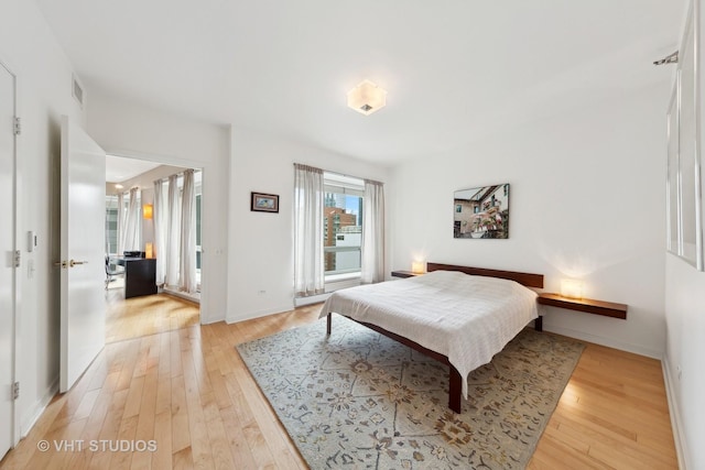 bedroom with light wood-style floors, visible vents, and baseboards