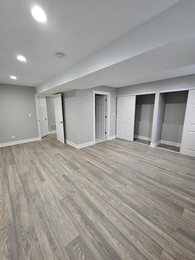 finished below grade area featuring light wood-type flooring, visible vents, and baseboards