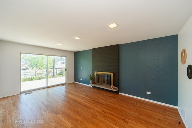 unfurnished living room with baseboards, a fireplace, visible vents, and wood finished floors