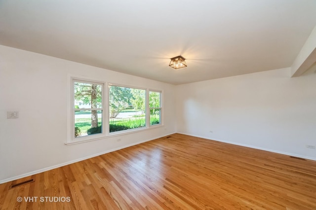 unfurnished room featuring light wood-style floors, baseboards, and visible vents