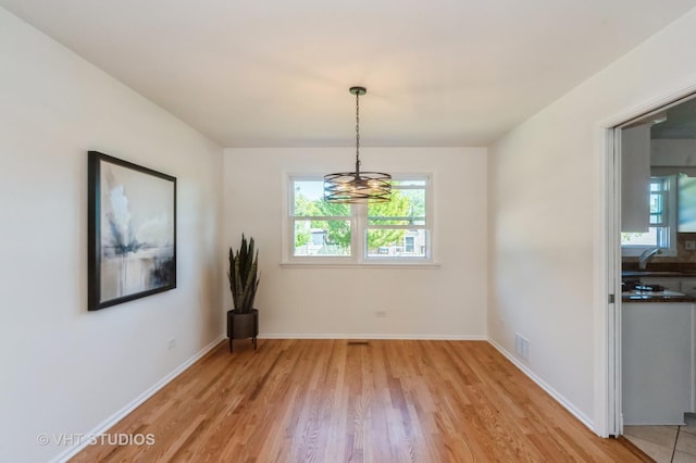 unfurnished dining area with visible vents, light wood-style flooring, and baseboards