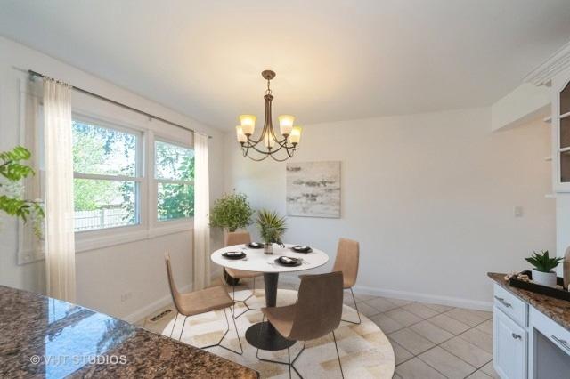 dining room with an inviting chandelier, baseboards, and light tile patterned flooring