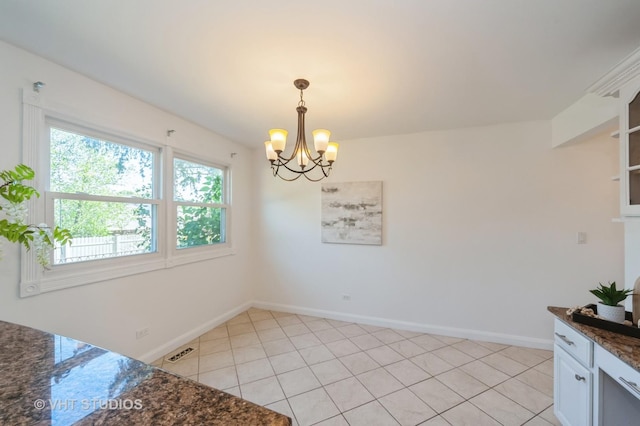 unfurnished dining area featuring baseboards, light tile patterned floors, visible vents, and an inviting chandelier