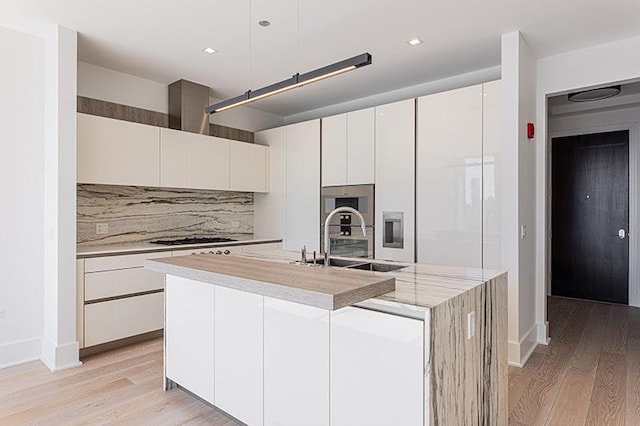 kitchen with light wood-style flooring, modern cabinets, white cabinets, and a sink