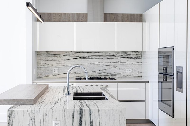 kitchen featuring backsplash, modern cabinets, white cabinets, and a sink